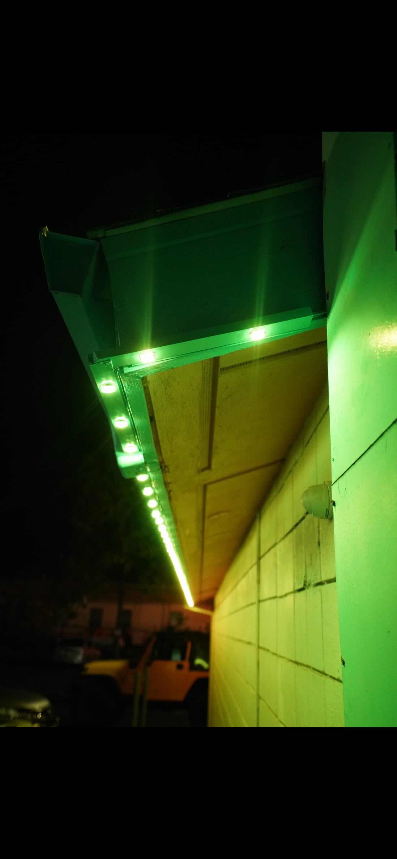 Green exterior lighting along a building eave